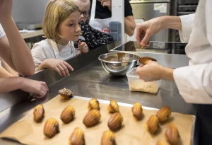 Enfant qui regarde la cheffe faire des madeleines