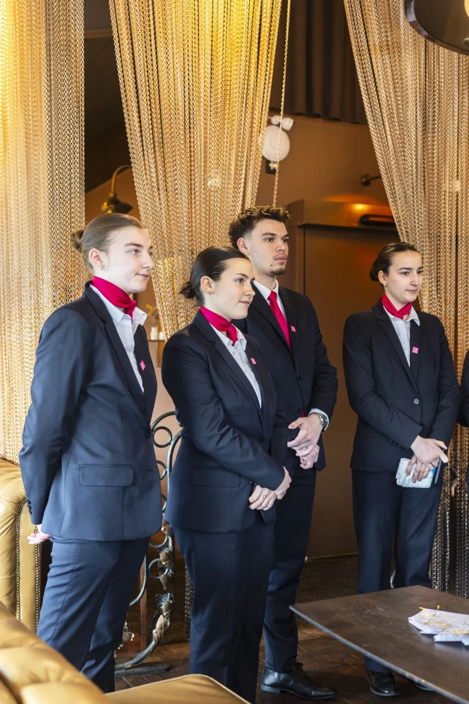 Élèves en tenue de service. debout dans un restaurant qui accueillent les clients.