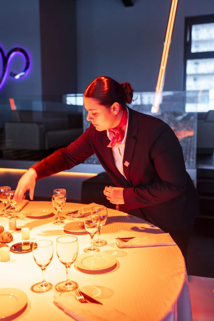Élève en tenu de service, préparant un table de restaurent.