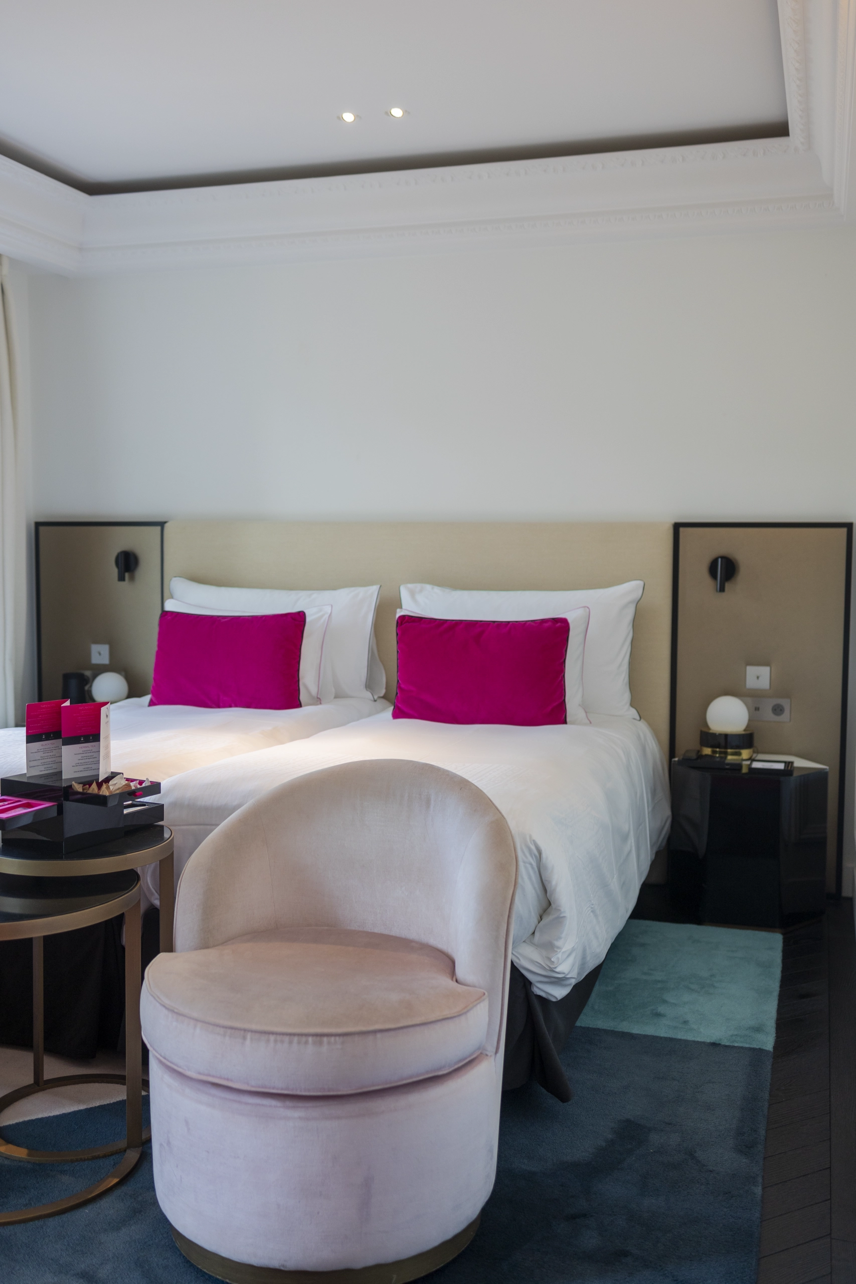 chambre d'hotel fauchon avec un lit blanc et des coussins roses