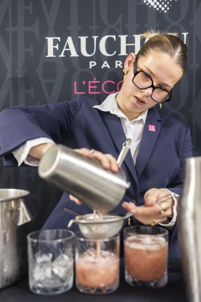 Élève préparant un cocktail avec un shaker.