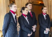 Élèves en tenue de service. debout dans un restaurant qui accueillent les clients.