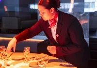 Élève en tenu de service, préparant un table de restaurent.